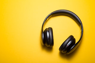Black wireless headphones on a bright yellow studio background